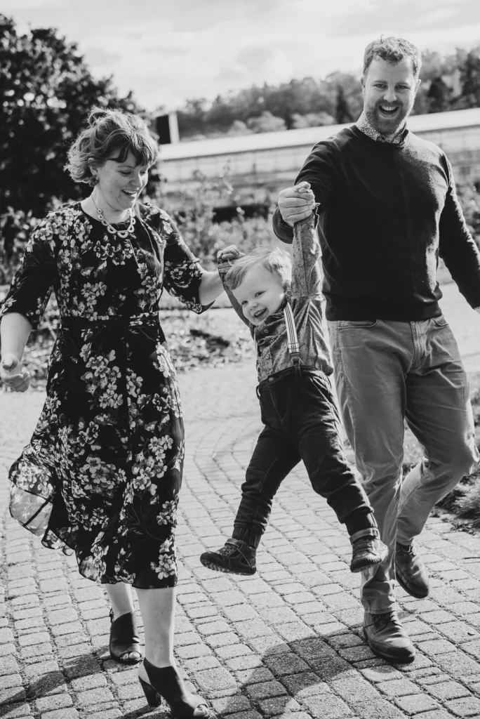 a mother and father swing their little boy by his arms - shot at Gage park in Hamilton, Ontario