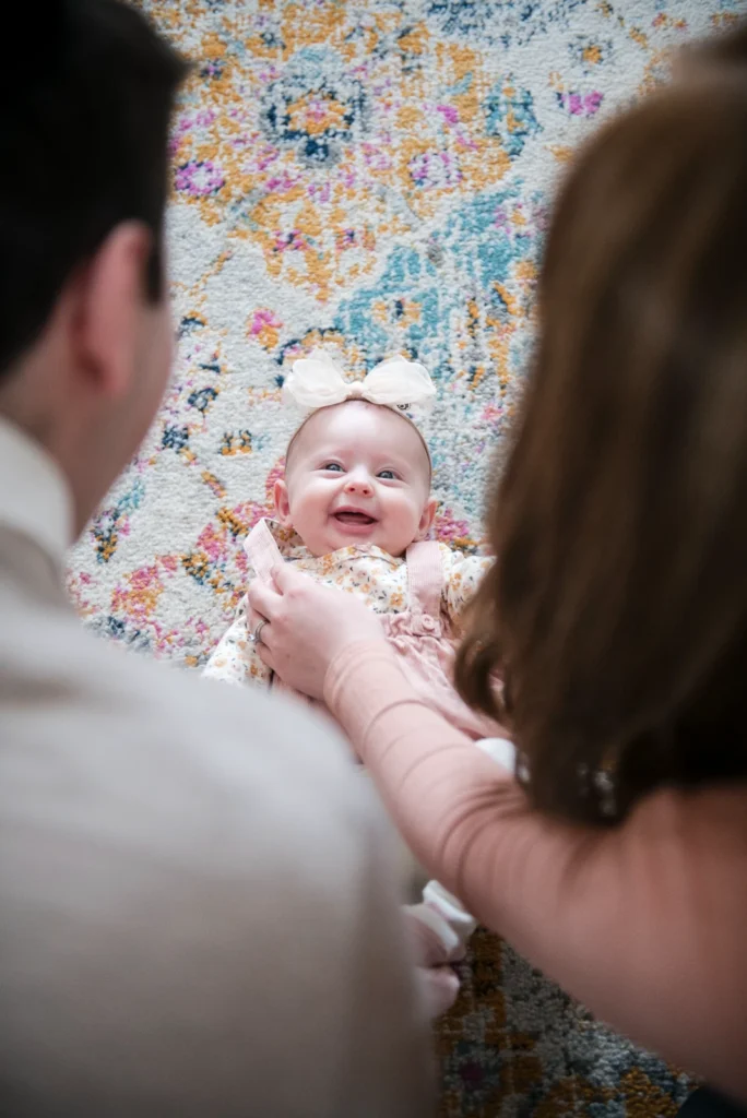 a couple plays with their baby who is laying on the ground