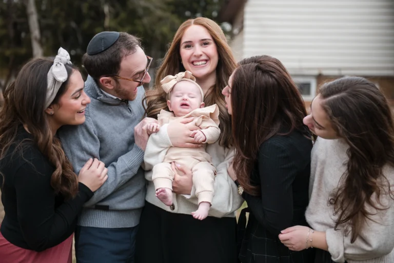 a woman holds her new baby as her siblings gather around and look at the baby