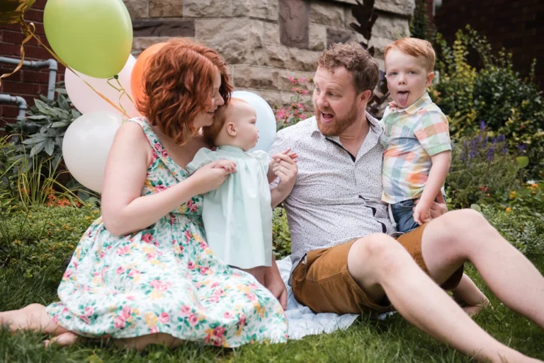 a family of four sit in their front yard playing with each other.