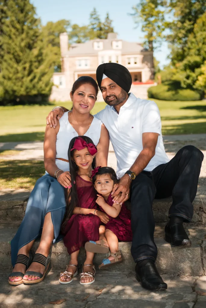 a family of four sit on stone stairs and look at the camera - a family portrait shot at Paletta Mansion in Burlington, Ontario