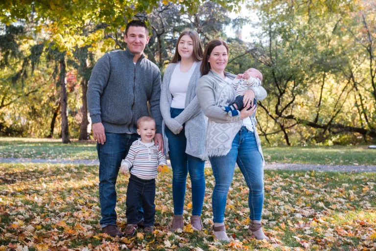 a family of five stand and smile at the camera - a family portrait shot in battlefield park in Hamilton, Ontario