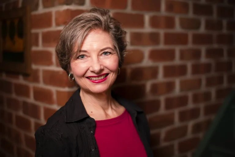 a choir director smiles while standing in front of a brick wall - a headshot shot by Hamilton headshot photographer : Pixelesque Photography