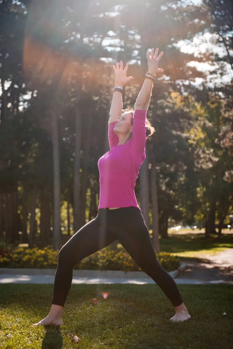 a yoga teacher in warrior pose with sunlight and trees in a park - a headshot shot by Hamilton headshot photographer : Pixelesque Photography