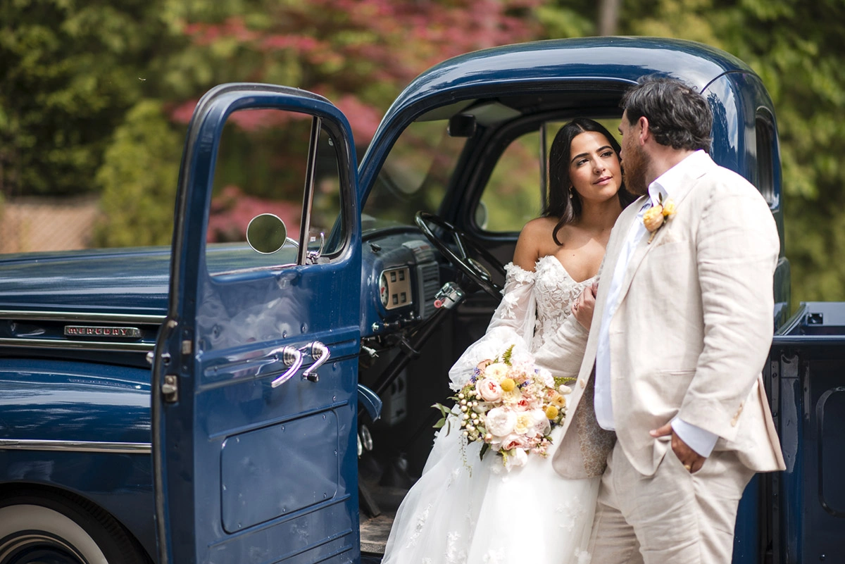 the wedding couple looks at each other while the bride is sat in a vintage truck. Shot by Pixelesque Photography - Hamilton Wedding Photographer.