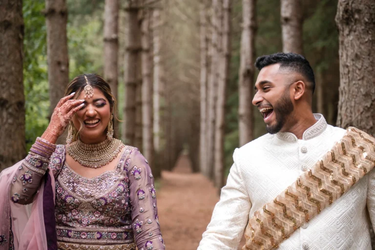 An Indian Bride and groom share a laugh on a tree lined path. Shot at Erin Estate by Pixelesque Photography - Hamilton Wedding Photographer.