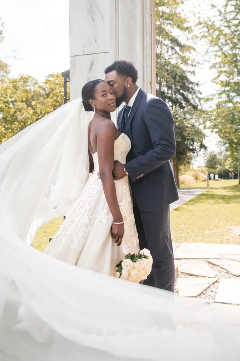 A groom kisses his bride as her veil flows. Shot at Guild Inn Estate, Scarborough by Pixelesque Photography - Hamilton Wedding Photographer.