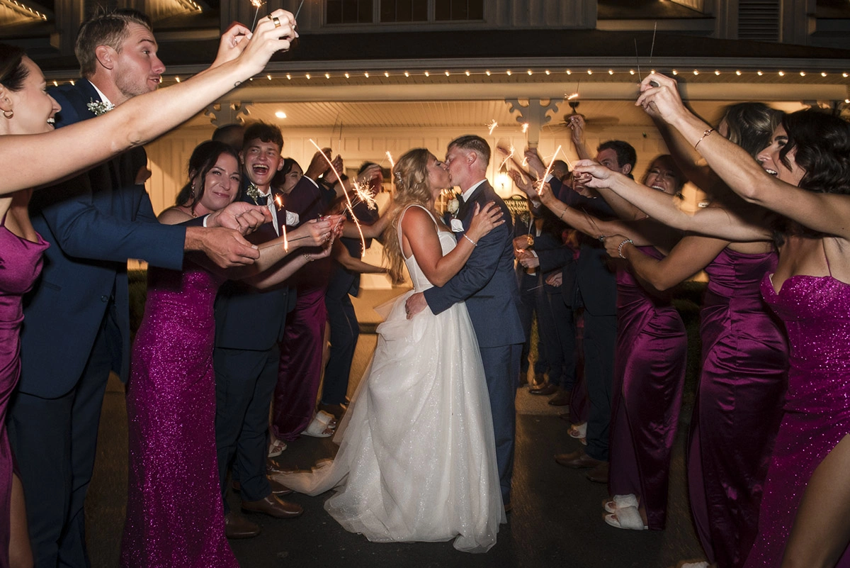 the wedding party wave sparklers around the couple as they kiss. Shot by Pixelesque Photography - Hamilton Wedding Photographer.