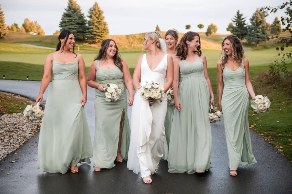 The bride and her bridesmaids walk down a path together. Shot at Whistle Bear Golf Club by Pixelesque Photography - Hamilton Wedding Photographer.