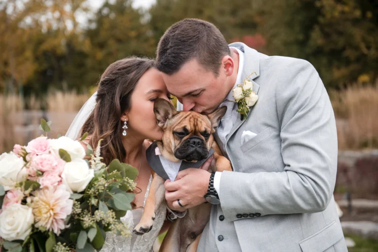 A wedding couple kisses their dog who is also wearing a little suit. Shot by Pixelesque Photography - Hamilton Wedding Photographer.
