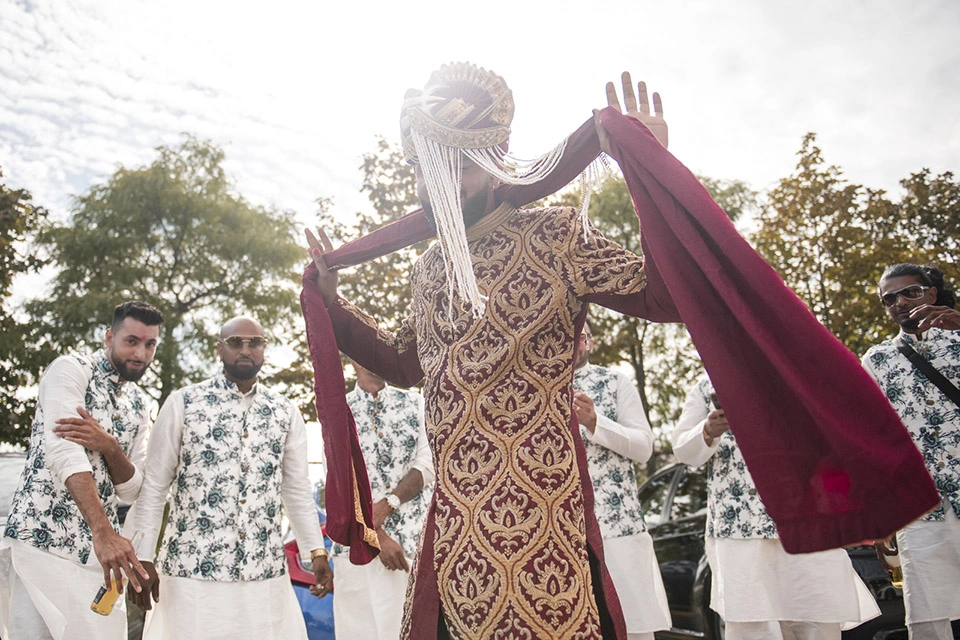 a groom in indian wedding garb dances as his groomsmen stand behind him. Shot by Pixelesque Photography - Hamilton Wedding Photographer.