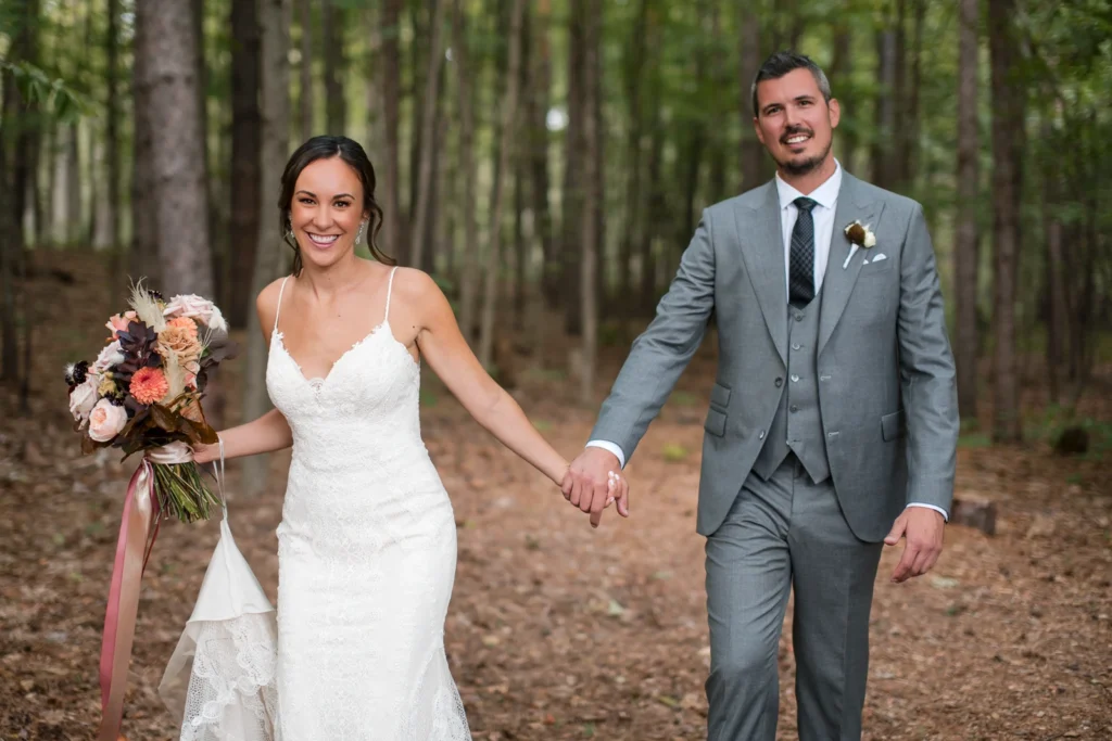 A bride and groom walk hand in hand through a forest. Shot by Pixelesque Photography - Hamilton Wedding Photographer.
