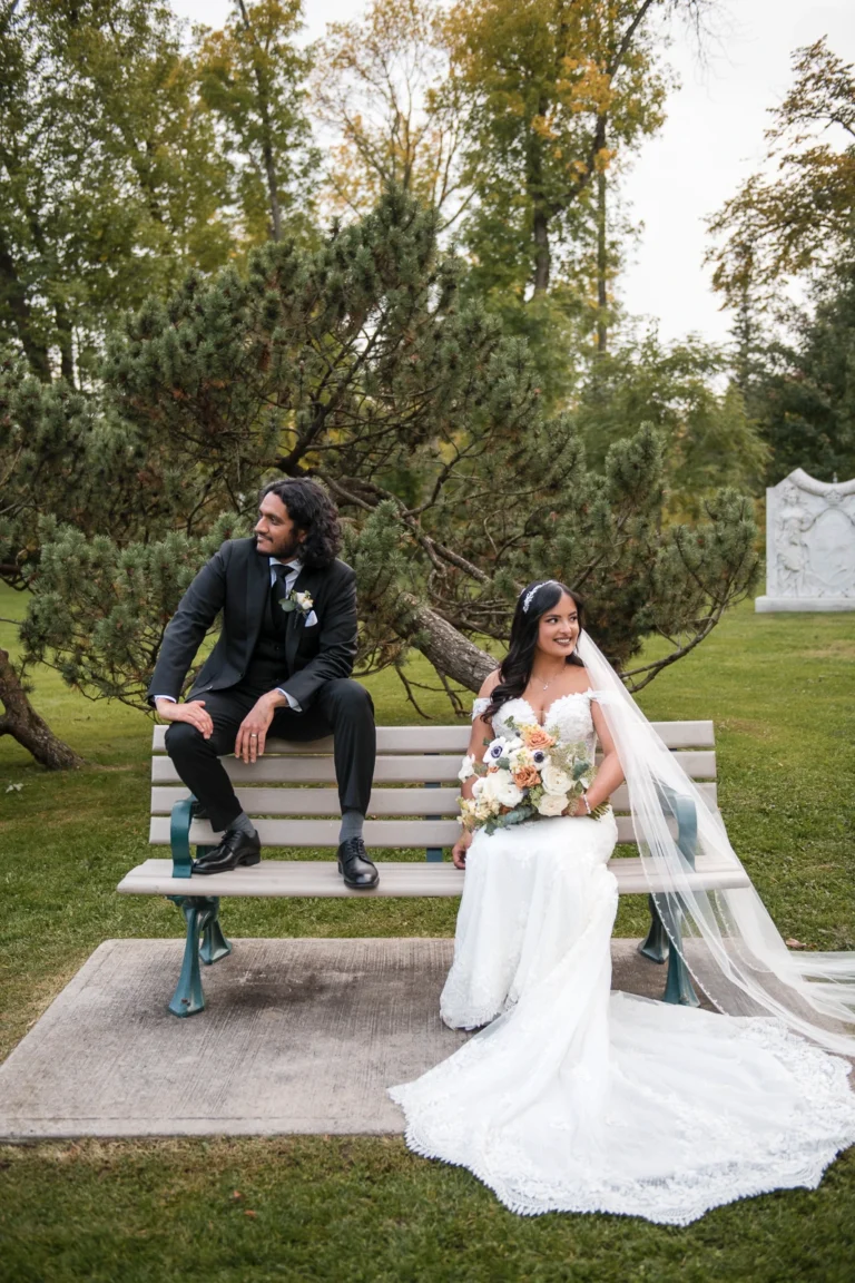 A bride and groom pose on a park bench. Shot at Guild Inn Estate Scarborough by Pixelesque Photography - Hamilton Wedding Photographer.