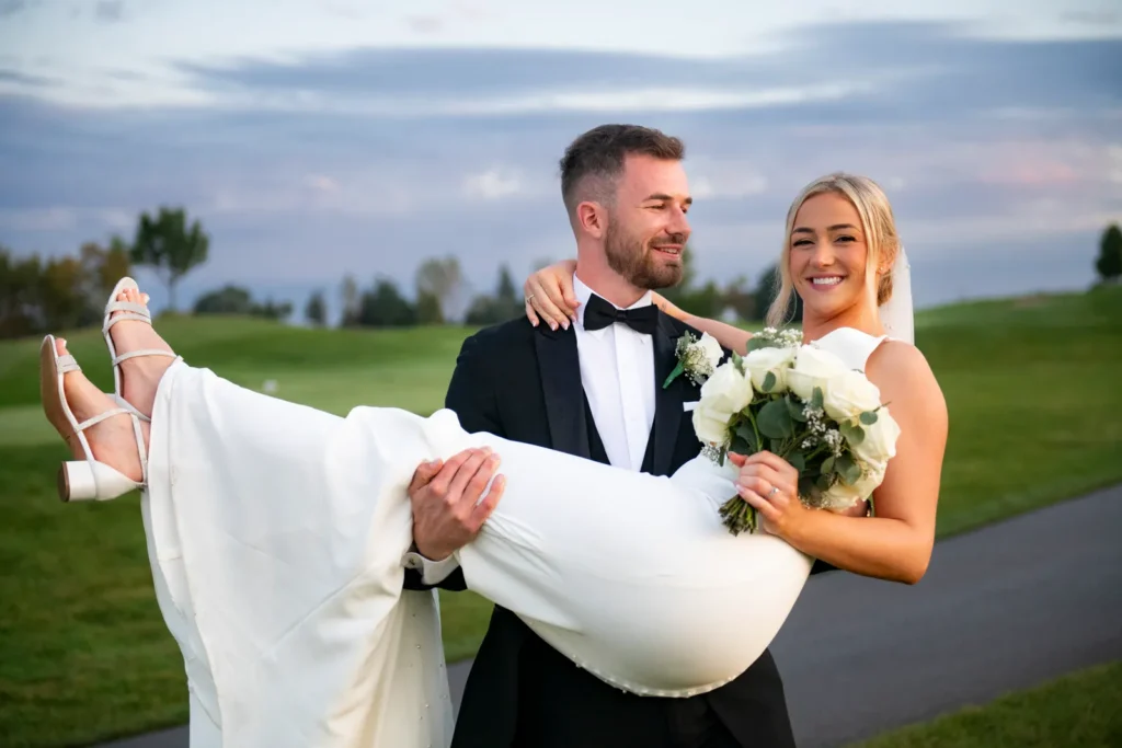After the Rains : Kayla & Kyle's Whistle Bear Golf Club Wedding 26 the groom carries the bride, she looks at the camera while he looks at her. Shot at Whistle Bear Golf Club by Pixelesque Photography - Hamilton Wedding Photographer.