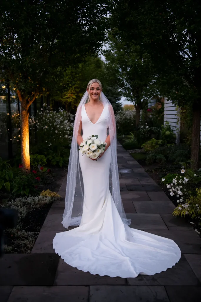 After the Rains : Kayla & Kyle's Whistle Bear Golf Club Wedding 29 the bride stands in a garden holding her flowers. Shot at Whistle Bear Golf Club by Pixelesque Photography - Hamilton Wedding Photographer.