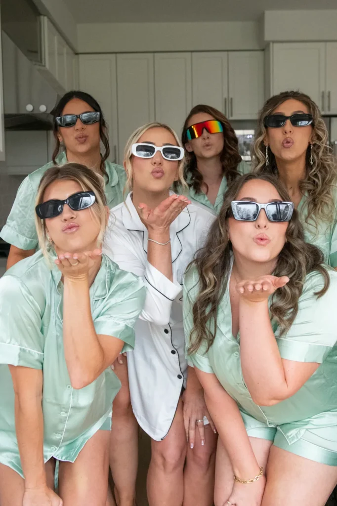 the bride and bridesmaids wear sunglasses and blow kisses at the camera. they are wearing matching pajamas. Shot at Whistle Bear Golf Club by Pixelesque Photography - Hamilton Wedding Photographer.