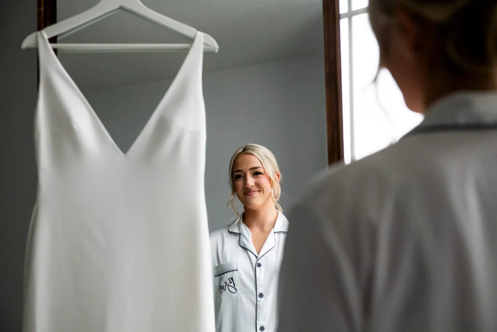 the bride looks at her dress and she is reflected in the mirror. Shot at Whistle Bear Golf Club by Pixelesque Photography - Hamilton Wedding Photographer.