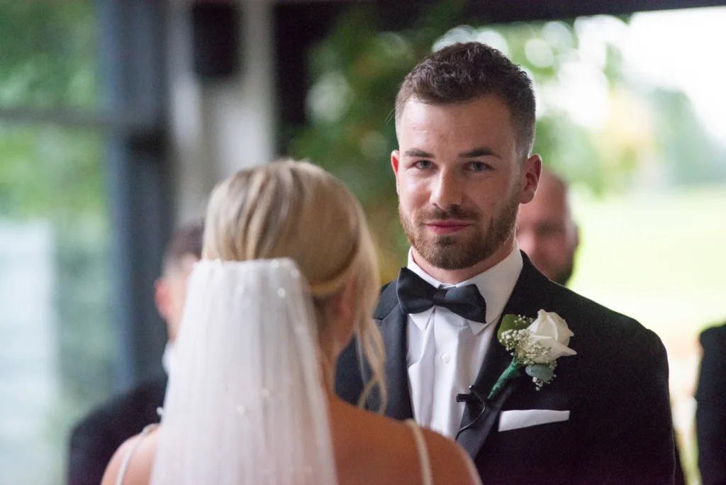 After the Rains : Kayla & Kyle's Whistle Bear Golf Club Wedding 10 the groom looks at the camera as he stands at the front of the aisle getting married. Shot at Whistle Bear Golf Club by Pixelesque Photography - Hamilton Wedding Photographer.