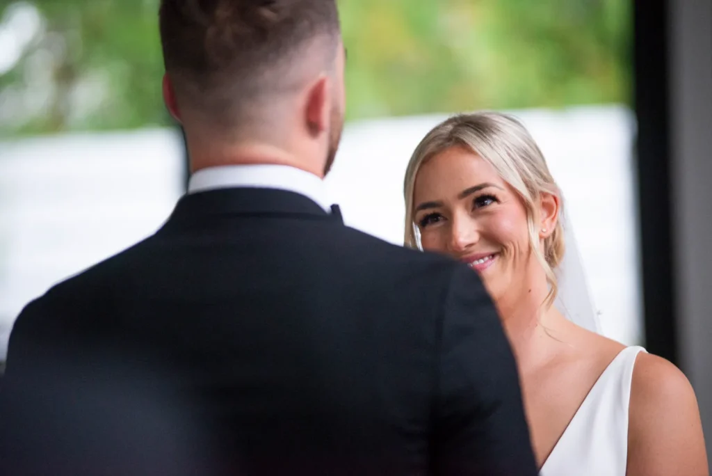 After the Rains : Kayla & Kyle's Whistle Bear Golf Club Wedding 11 the bride looks at the groom with a big smile as they get married. Shot at Whistle Bear Golf Club by Pixelesque Photography - Hamilton Wedding Photographer.