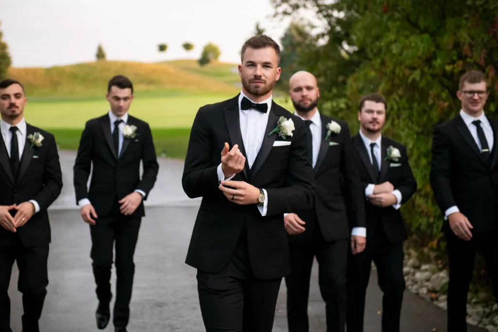 the groom fixes his cuff as he walks towards the camera with his groomsmen around him. Shot at Whistle Bear Golf Club by Pixelesque Photography - Hamilton Wedding Photographer.