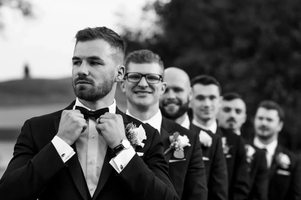 the groom fixes his bowtie as the groomsmen are in line behind him. Shot at Whistle Bear Golf Club by Pixelesque Photography - Hamilton Wedding Photographer.