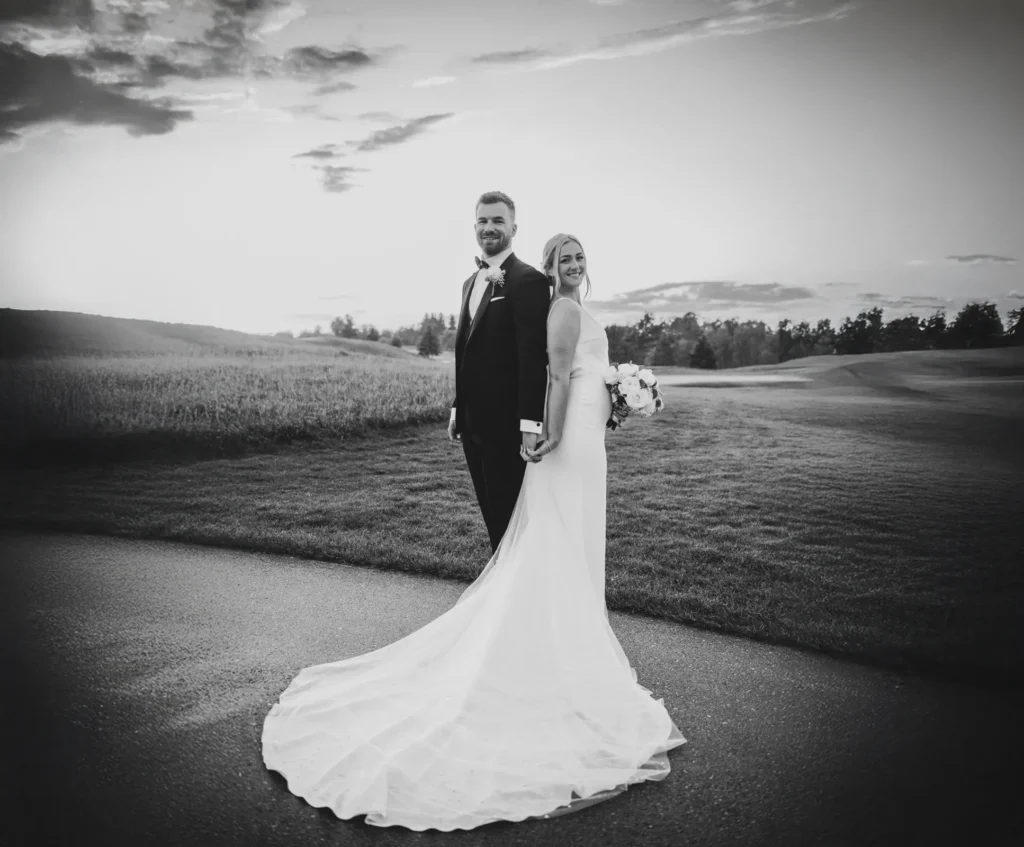 the couple stand back to back and her dress covers the ground around them. Shot at Whistle Bear Golf Club by Pixelesque Photography - Hamilton Wedding Photographer.