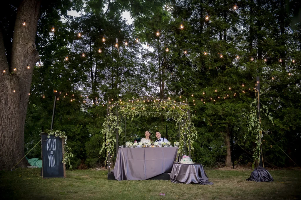 a wedding couple sit at the sweetheart table in a backyard wedding - hamilton wedding venue - shot by hamilton wedding photographer- Pixelesque Photography