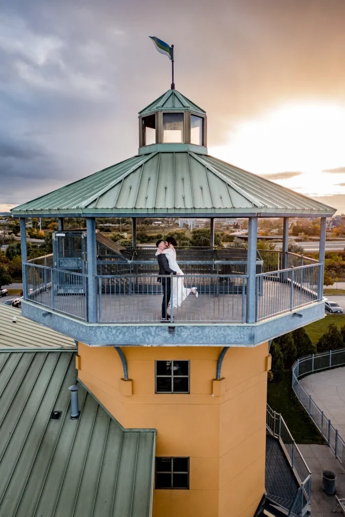 a drone shot of a wedding couple sharing a kiss at the top of a lighthouse at the lakeview by carmens - hamilton wedding venue - shot by hamilton wedding photographer- Pixelesque Photography