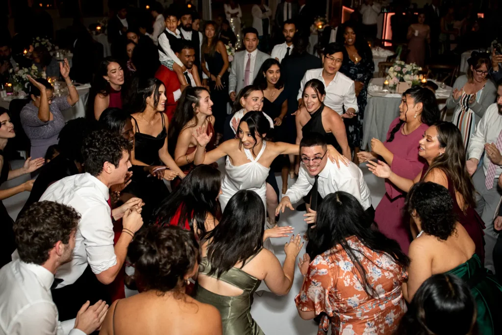 the couple surrounded by friends and family on the dance floor. One of many beautiful moments from a wedding at Harding Waterfront Estate in Oakville, by Pixelesque Photography - Hamilton Wedding Photographer.
