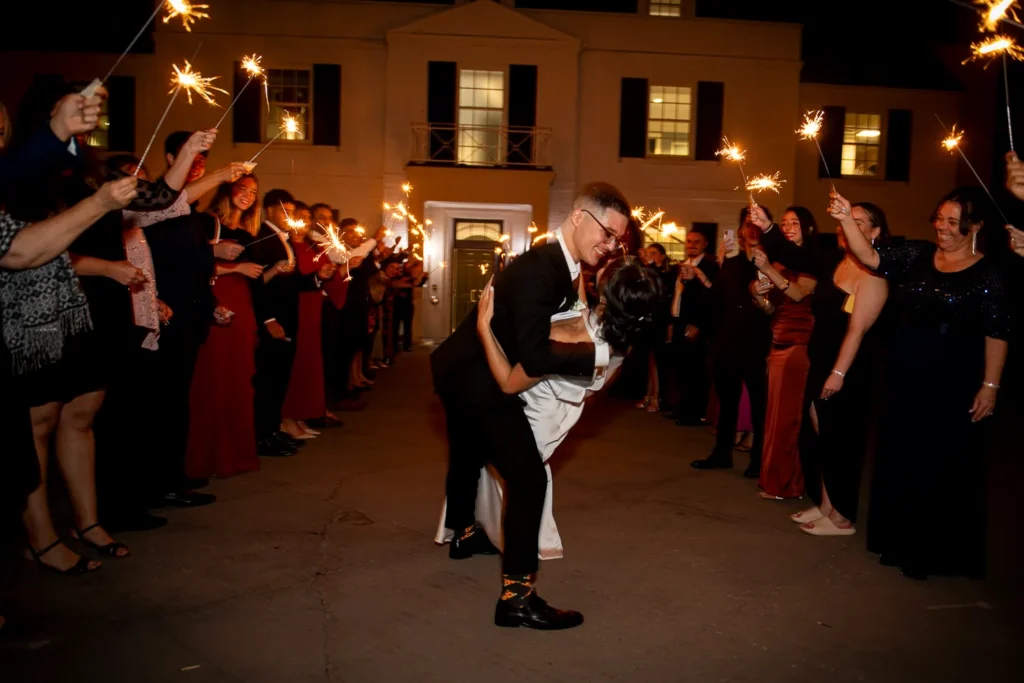 the couple share a dip and kiss at the end of a sparkler exit. One of many beautiful moments from a wedding at Harding Waterfront Estate in Oakville, by Pixelesque Photography - Hamilton Wedding Photographer.