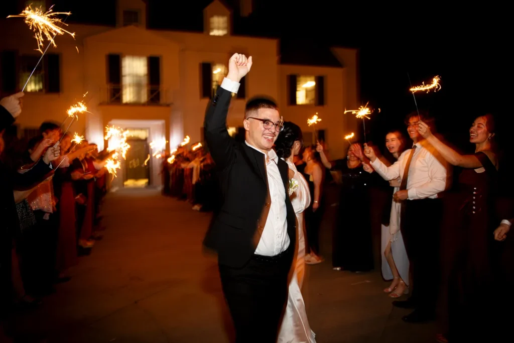 the groom pumps his fists as he does a sparkler exit with his bride. One of many beautiful moments from a wedding at Harding Waterfront Estate in Oakville, by Pixelesque Photography - Hamilton Wedding Photographer.