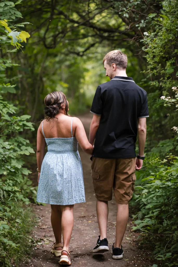A rear view of a couple walking hand in hand through the woods. Engagement Session Shot at Sherman Falls, Ancaster, by Pixelesque Photography - Hamilton Wedding Photographer.