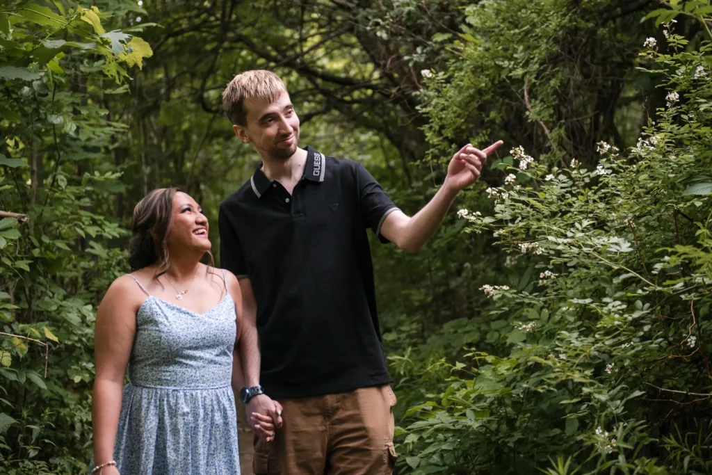 A man points something out in the woods to his partner. Engagement Session Shot at Sherman Falls, Ancaster, by Pixelesque Photography - Hamilton Wedding Photographer.