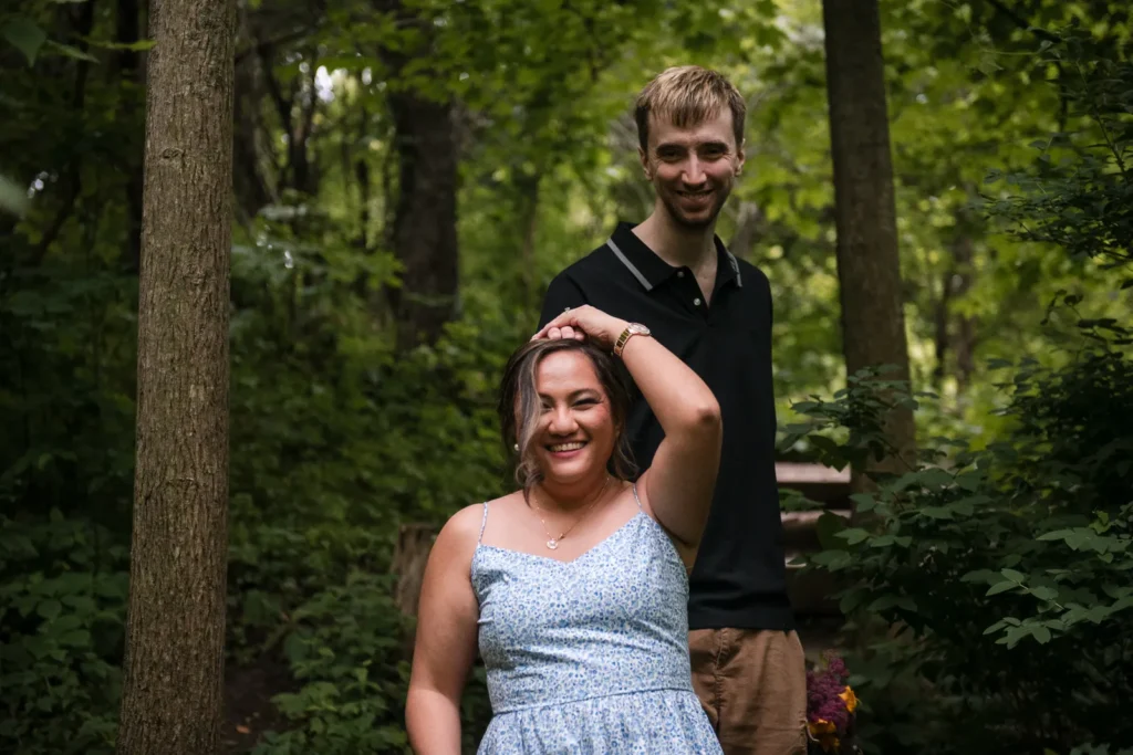 A couple walks through the woods with his hand on her head. Engagement Session Shot at Sherman Falls, Ancaster, by Pixelesque Photography - Hamilton Wedding Photographer.