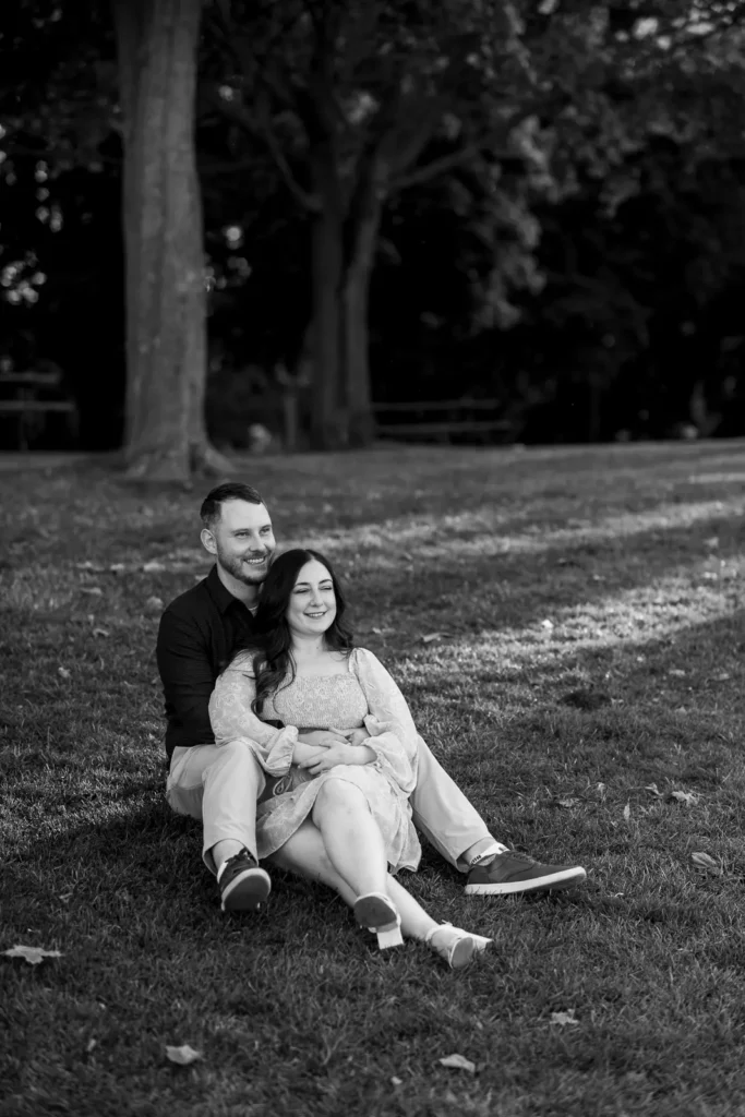 a couple sit on the grass with each other. Part of an engagement shoot Shot in Niagara-on-the-lake by Pixelesque Photography.