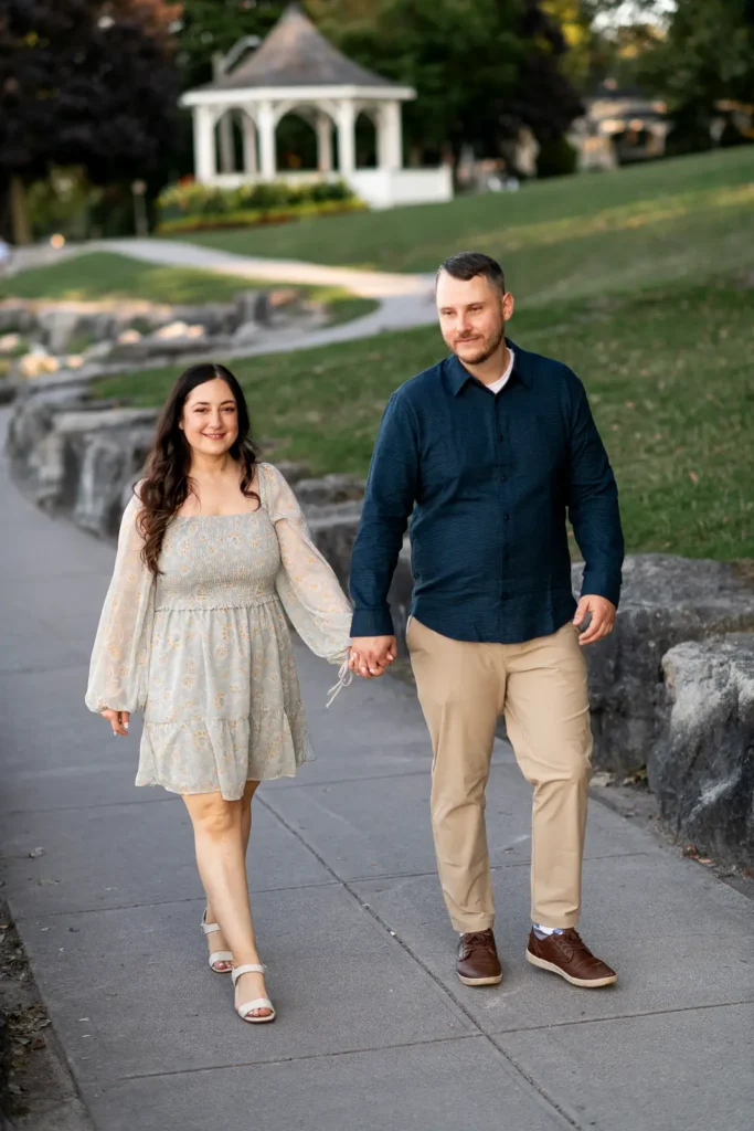 a couple walk along a path with the iconic queen's royal park gazebo in the background.