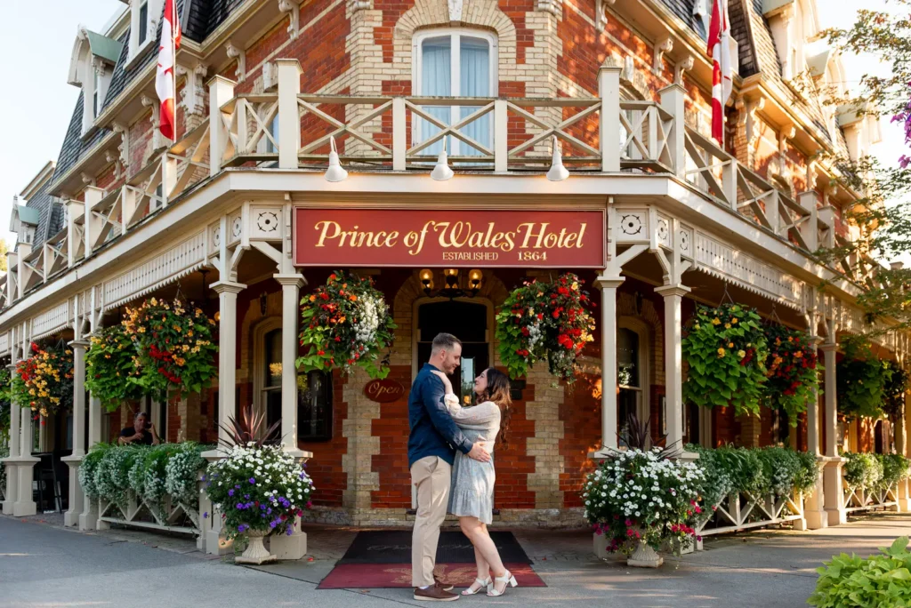 a couple hold each other face to face as they stand in front of a the iconic Prince of Wales hotel. Shot in Niagara-on-the-lake by Pixelesque Photography.