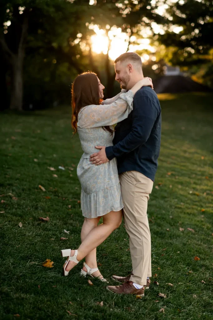 a couple hold each other and look into each other's eyes as the sun bursts behind them. Part of an engagement shoot Shot in Niagara-on-the-lake by Pixelesque Photography.