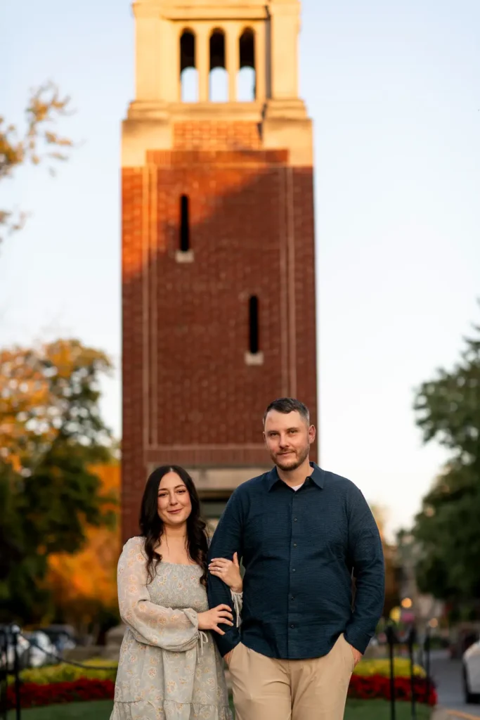 a couple walk in front of the iconic NOTL clock tower as they walk along. Part of an engagement shoot Shot in Niagara-on-the-lake by Pixelesque Photography.