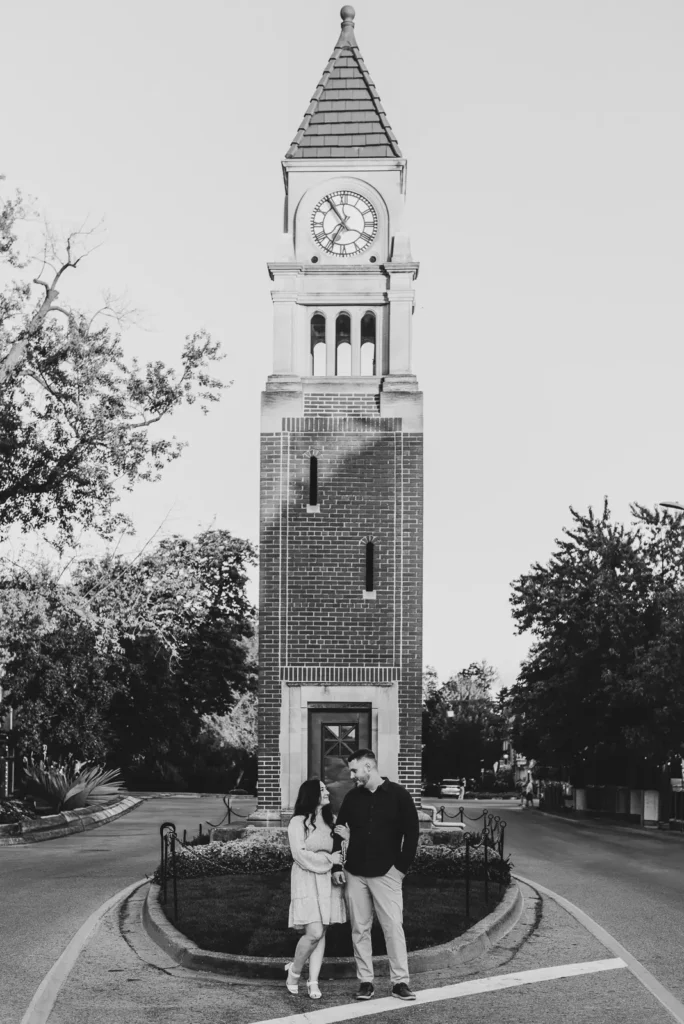 a couple pose arm in arm in front of the iconic NOTL clock tower. Part of an engagement shoot Shot in Niagara-on-the-lake by Pixelesque Photography.