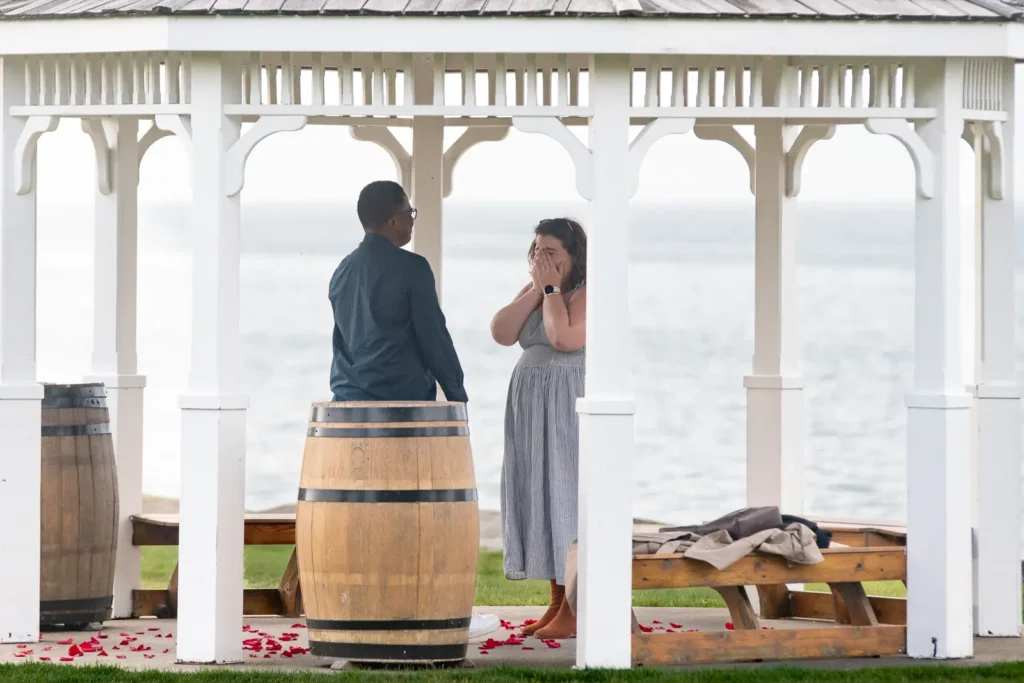 Emotional engagement moment at Konzelmann Estate gazebo with rose petals and waterfront views