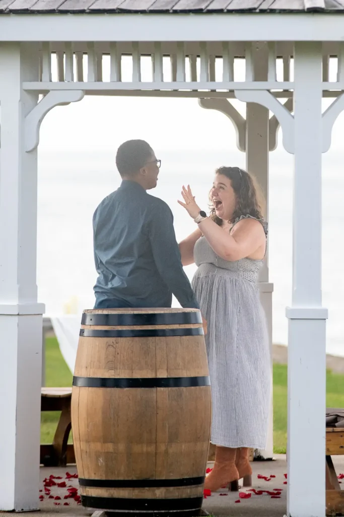 Emotional engagement moment at Konzelmann Estate gazebo with rose petals and waterfront views