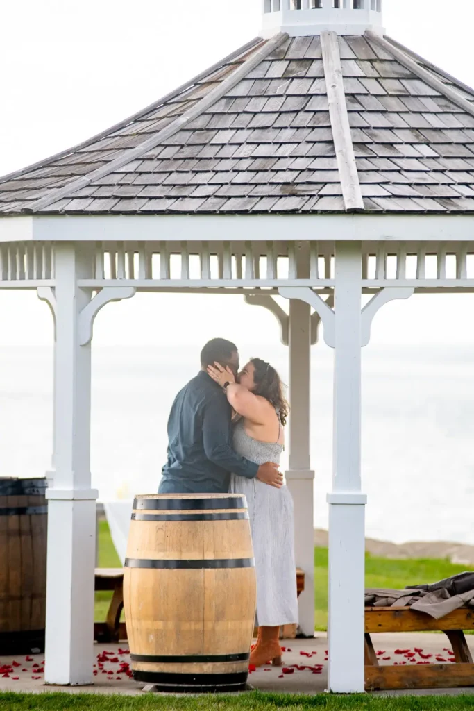 Emotional engagement moment at Konzelmann Estate gazebo with rose petals and waterfront views
