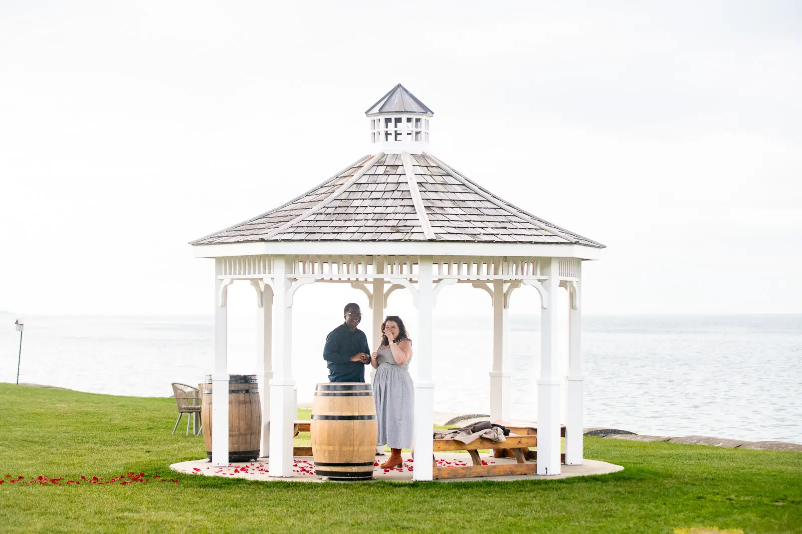 Emotional engagement moment at Konzelmann Estate gazebo with rose petals and waterfront views