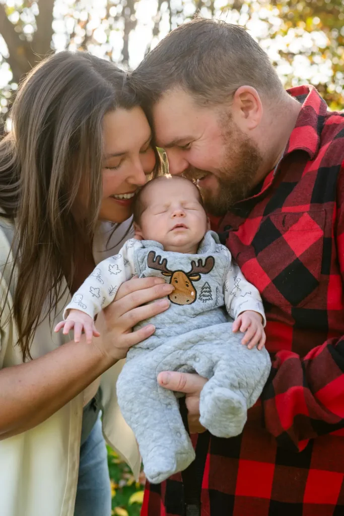 a couple go to give their newborn baby a kiss on his head as he sleeps. Shot at bayfront park by Pixelesque photography - Hamilton Family Photographer