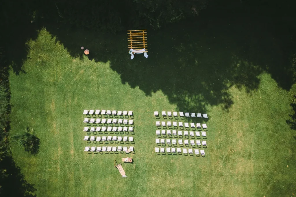 Shadows from trees fall upon the guests' seats and the wedding arbor. A wedding day drone photograph shot by Pixelesque Photography - Hamilton wedding Photographer.