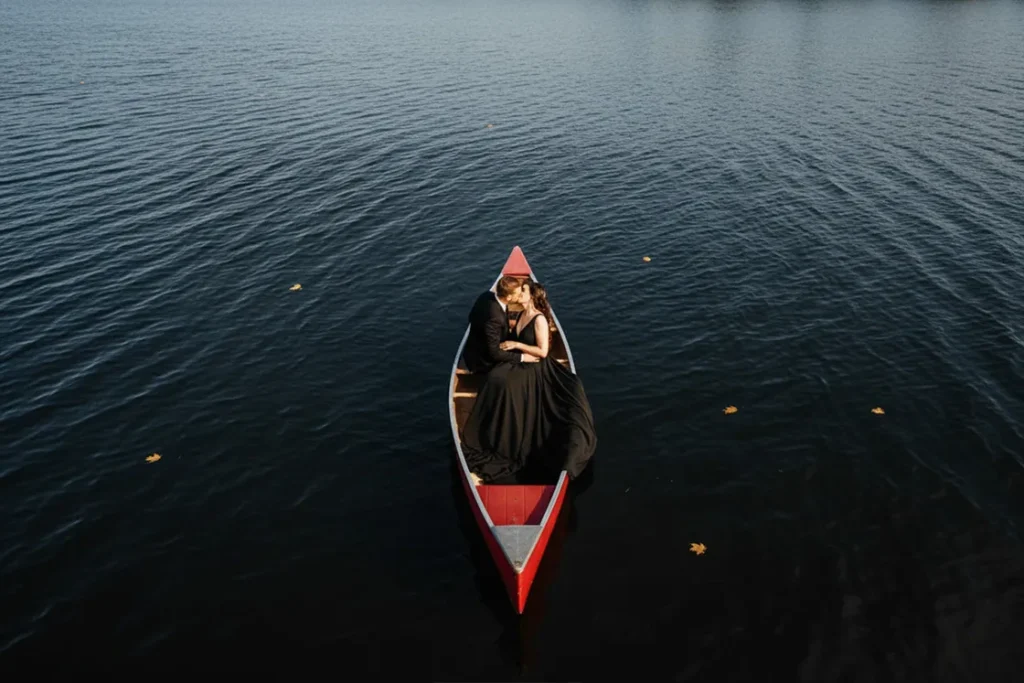 A groom kisses his bride who is wearing a black wedding dress in a canoe in a parry sound lake. A wedding day drone photograph shot by Pixelesque Photography - Hamilton wedding Photographer.