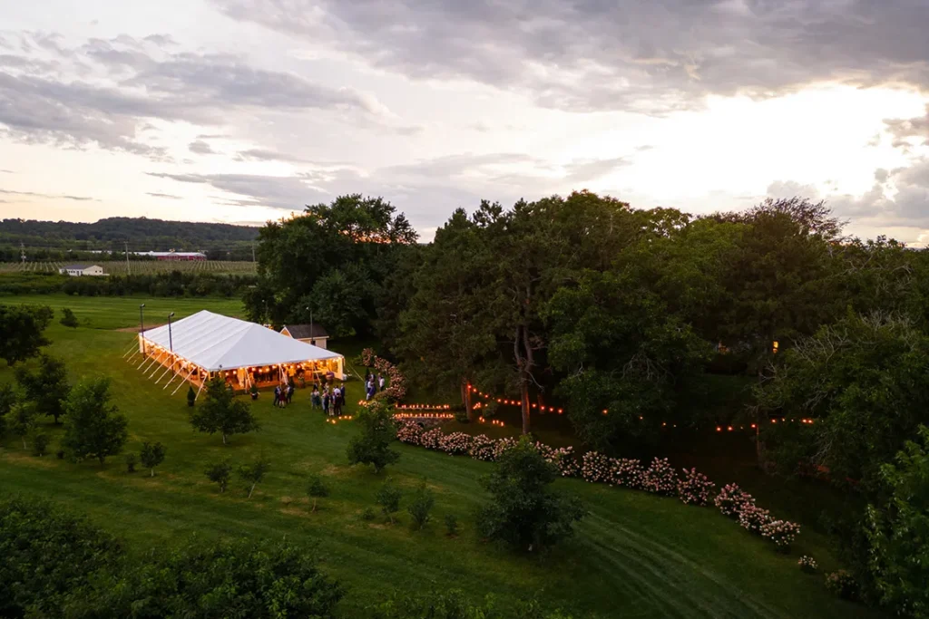 The moody lights of the reception tent glow in the night at Cherry Avenue Farms. A wedding day drone photograph shot by Pixelesque Photography - Hamilton wedding Photographer.