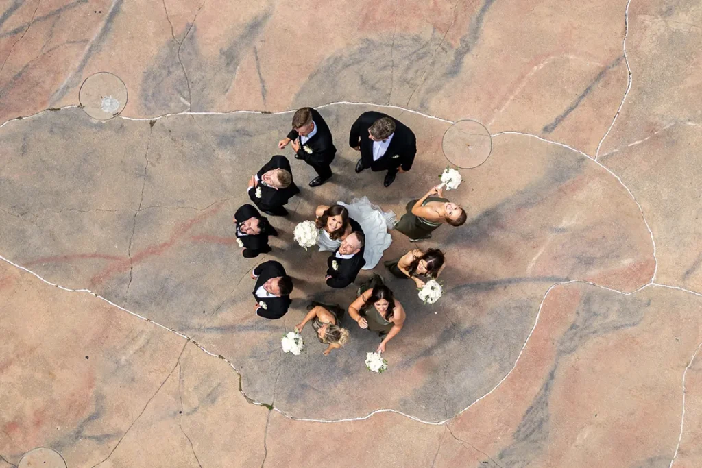 A couple and their surrounding wedding party stand on some beautiful rock floor at McMichael Gallery in Vaughan. A wedding day drone photograph shot by Pixelesque Photography - Hamilton wedding Photographer.