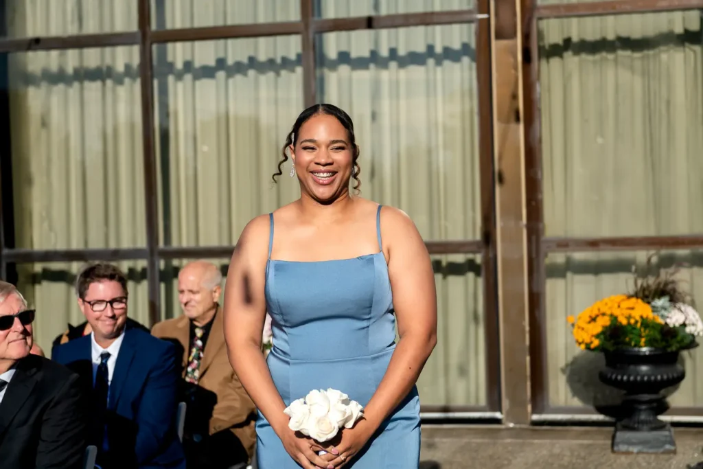 a bridesmaid laughs as she walks down the aisle. Shot at Carmen's event centre, Hamilton by Pixelesque Photography.